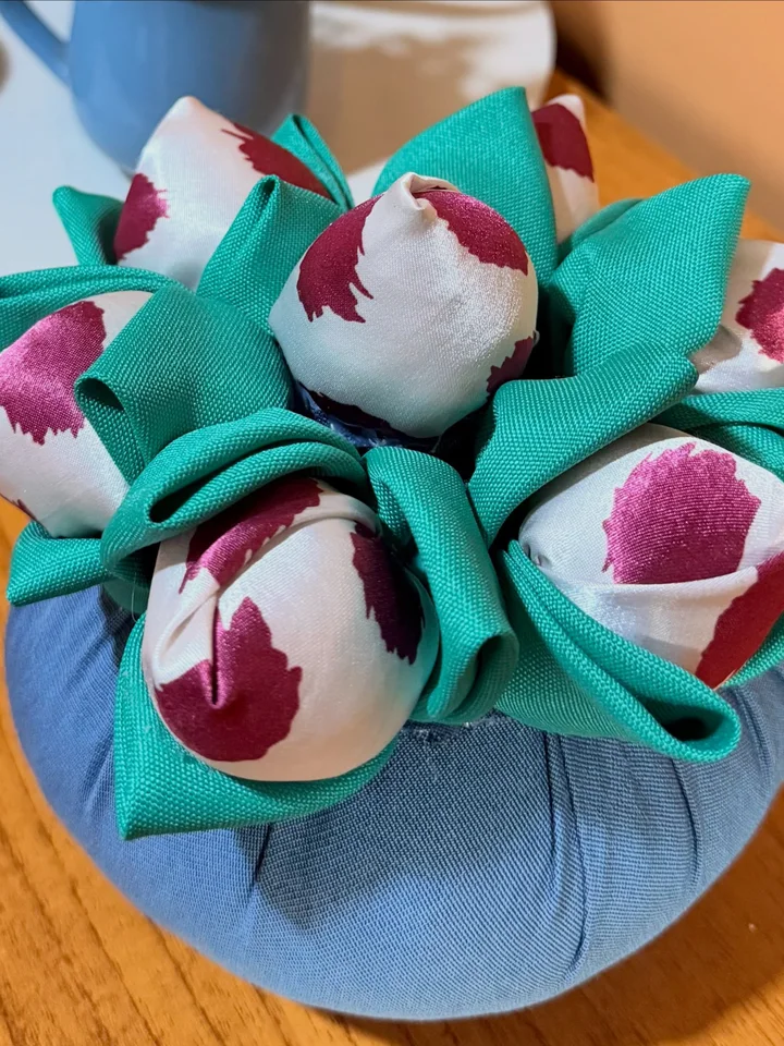 Detalhe das folhas turquesa e da estampa floral em uma flor de pano