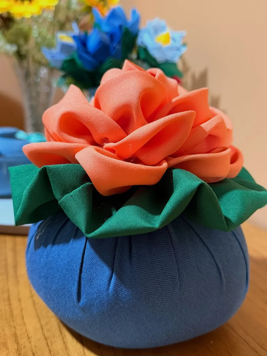 Peso de porta artesanal azul com uma grande flor de tecido coral e folhas verdes